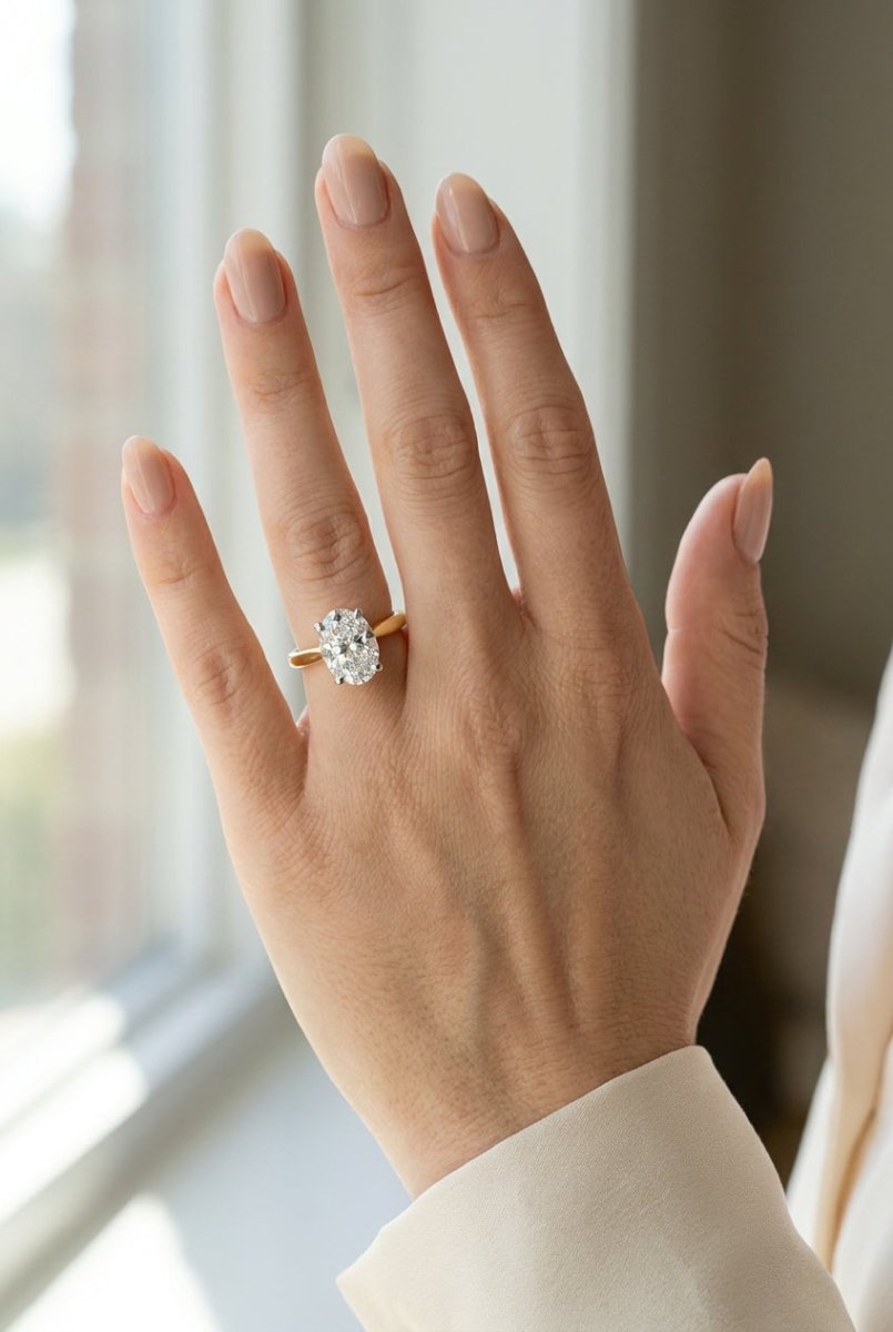 Full hand view showing scale of 2 carat oval engagement ring on woman ring finger with soft natural light
