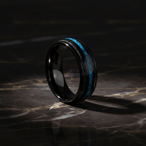ANTONAS — Luxury 3/4 angle on dark marble — men's tungsten wedding ring.