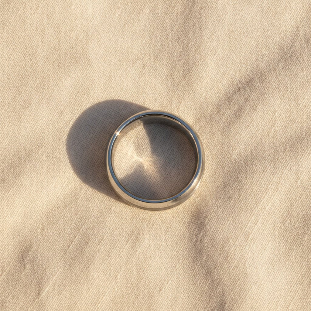 DEFIANCE silver tungsten domed wedding band with a single brushed vertical stripe running around the center and polished sides macro detail overhead flat lay
