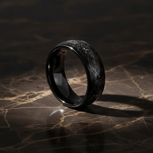 DOMINATOR — Luxury 3/4 angle on dark marble — men's tungsten wedding ring.