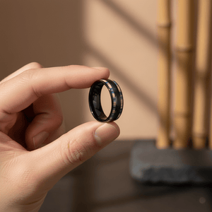 DUNLAP — Held between fingers close-up — men's tungsten wedding ring.