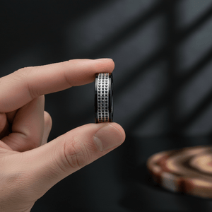 GRAVEL — Held between fingers close-up — men's tungsten wedding ring.