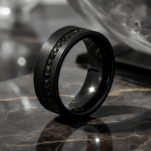 GROOVIX — Luxury 3/4 angle on dark marble — men's tungsten wedding ring.