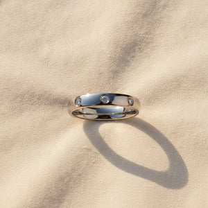 ISABELLA domed white tungsten wedding band with three small diamond accent stones set in a row on the center of the band and polished edges macro detail overhead flat lay