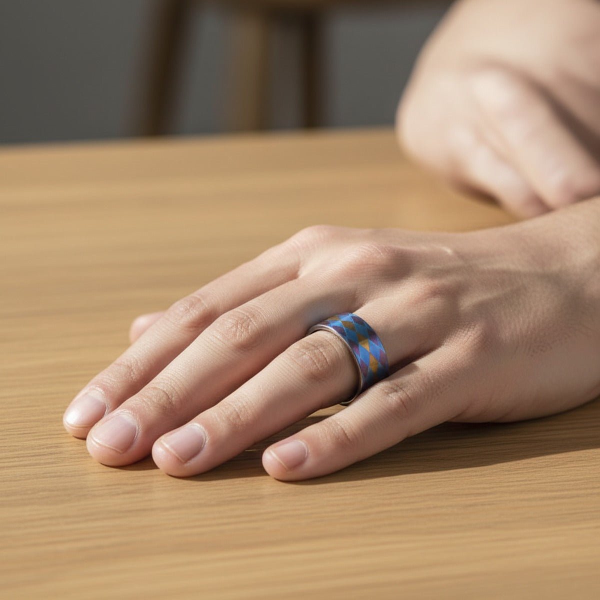 MAJESTIC flat titanium ring worn on a male hand resting on light wood, lifestyle scene