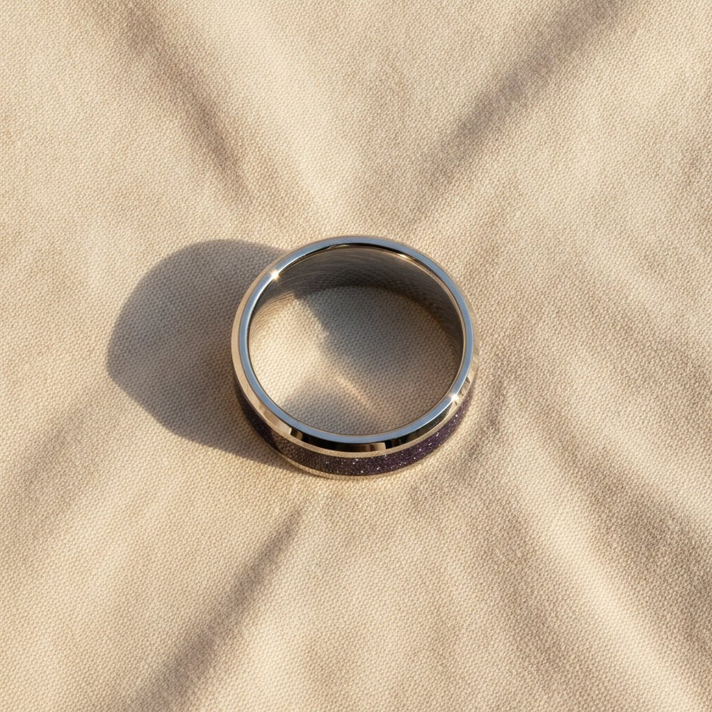 MAKI polished silver tungsten wedding band with sparkling purple goldstone inlay running around the band and polished beveled edges macro detail overhead flat lay