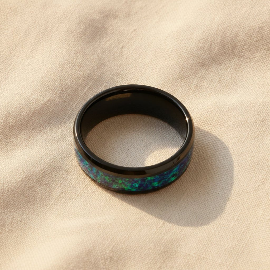 PULSAR black ceramic wedding band with emerald green and sapphire blue color opal inlay running around the band and polished beveled edges macro detail overhead flat lay