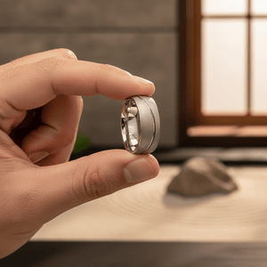 ROUGHZEN — Held between fingers close-up — men's tungsten wedding ring.