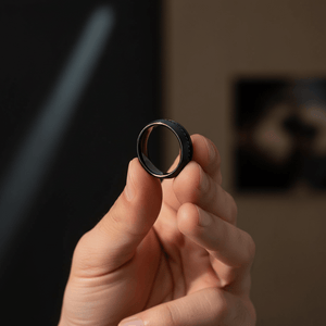 SANCHO — Held between fingers close-up — men's tungsten wedding ring.