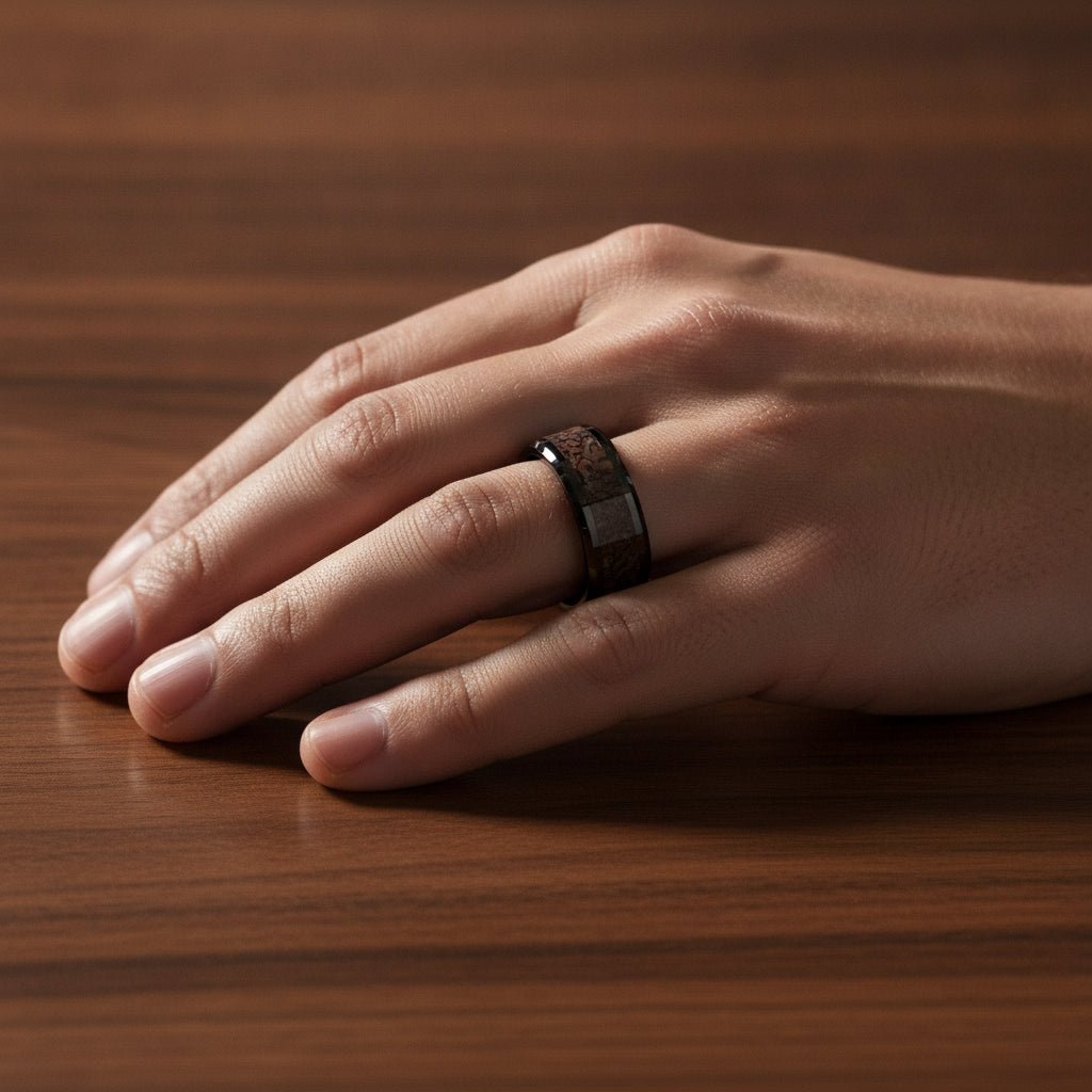 SILURIAN black ceramic ring with brown dinosaur bone inlay running around the band and polished beveled edges worn on man's hand resting on walnut wood, lifestyle photo