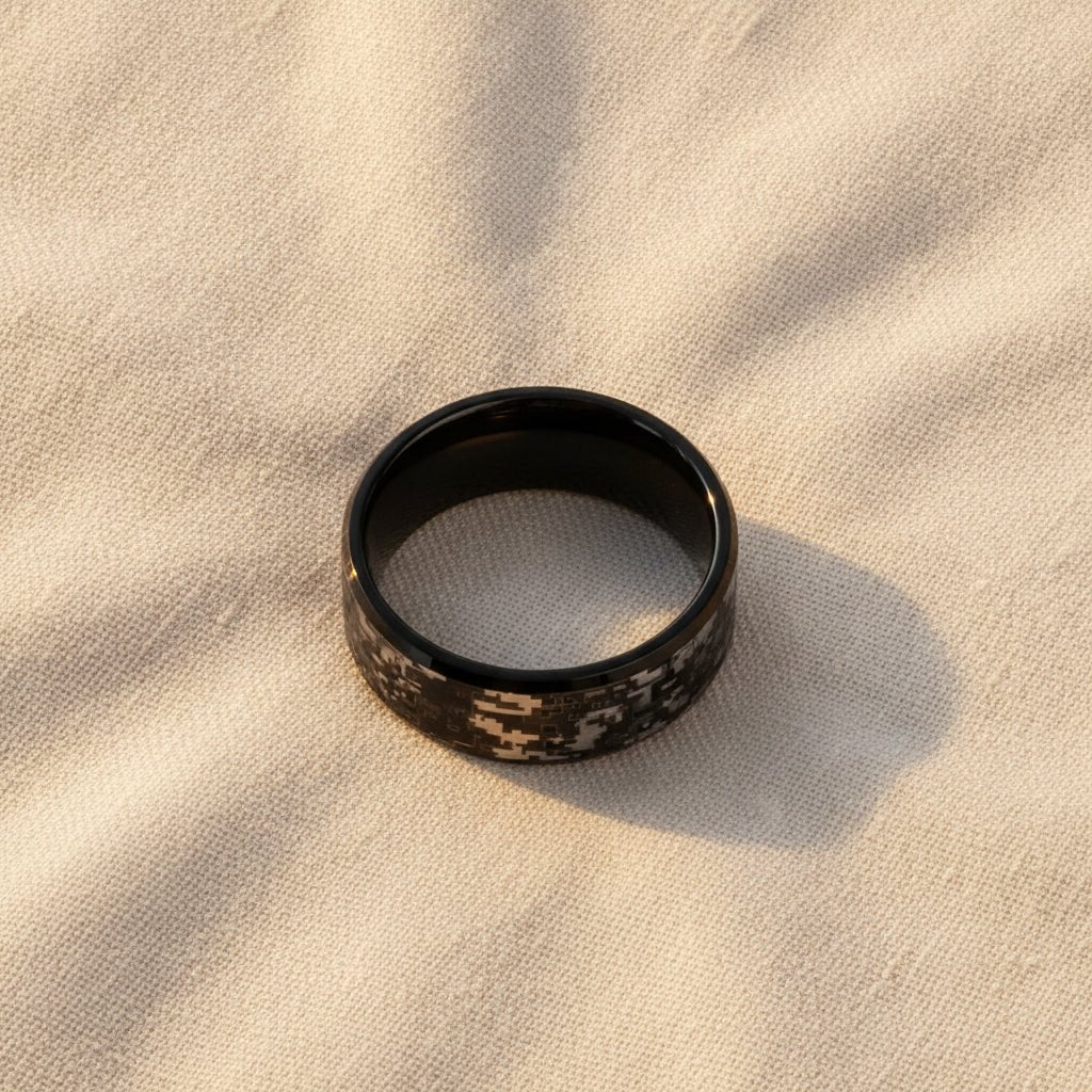 SMOKESCREEN black tungsten carbide wedding band with engraved digital camouflage pattern running around the band and polished edges macro detail overhead flat lay