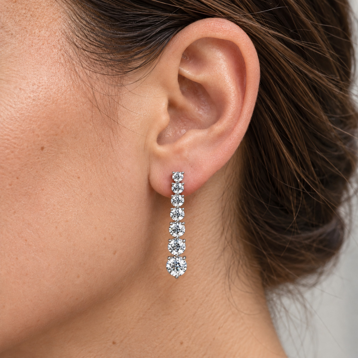 Graduated lab-grown diamond earrings in sterling silver, worn on the ear, lifestyle photo
