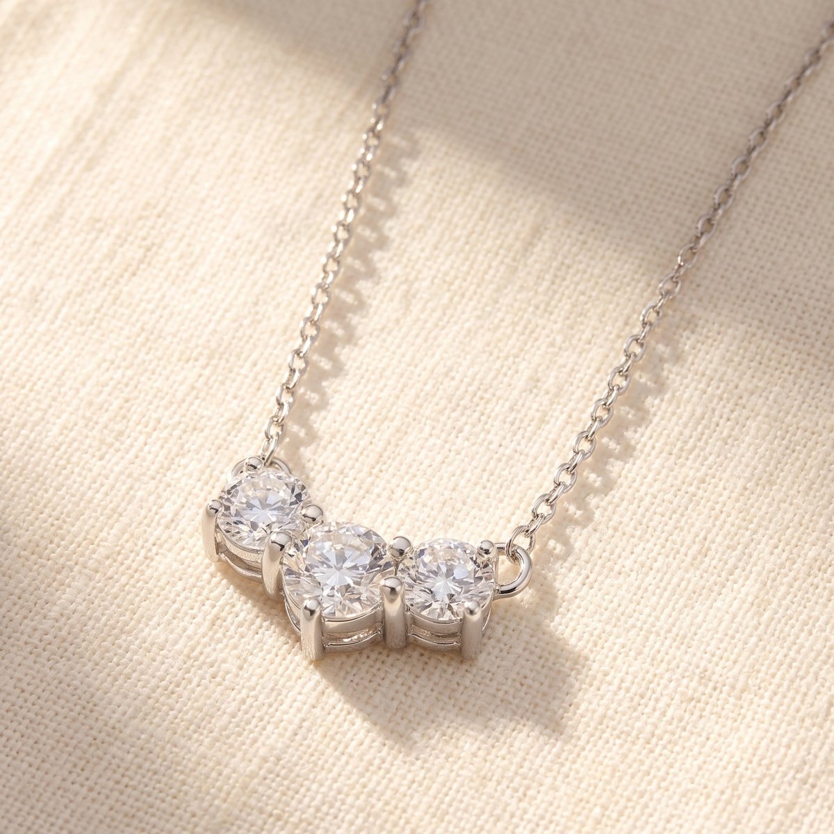 Three Stone Diamond Necklace 925 silver lab grown diamond necklace styled flat lay on cream linen
