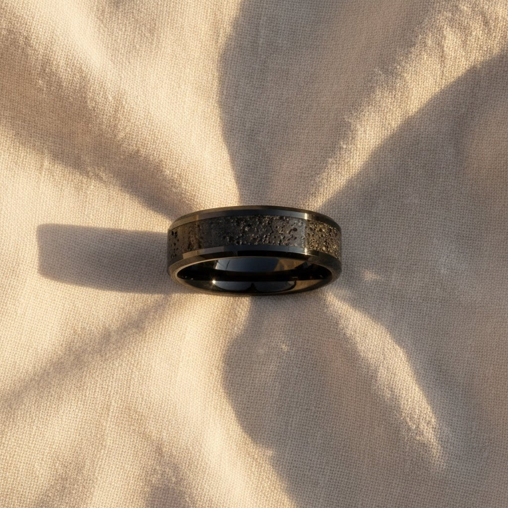 VESUVIUS polished black ceramic wedding band with black and gray lava rock stone inlay running around the band and polished beveled edges macro detail overhead flat lay