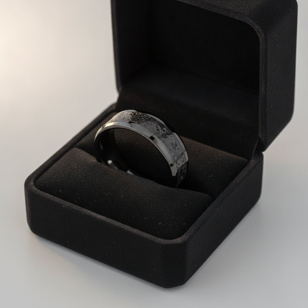 VESUVIUS polished black ceramic wedding band with black and gray lava rock stone inlay running around the band and polished beveled edges nested in a black velvet ring box, editorial jewelry shot