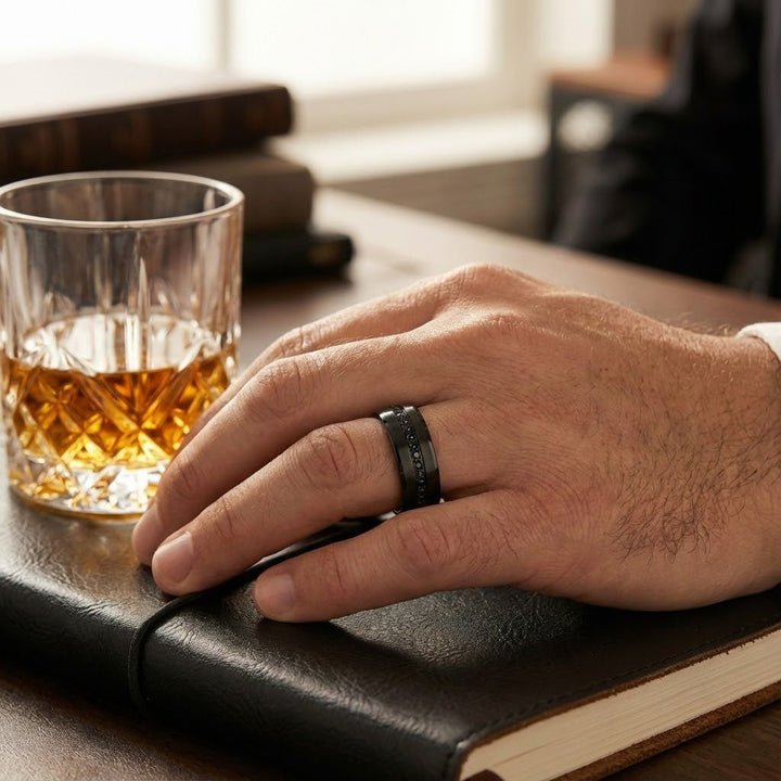Mans ring finger near a whiskey glass with a Matte Black APODIS Tungsten Ring - Flat Eternity Band with Black Diamond Stimulant