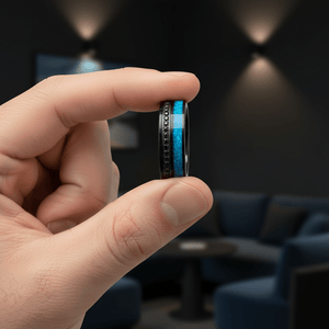 AQUORION — Held between fingers close-up — men's tungsten wedding ring.