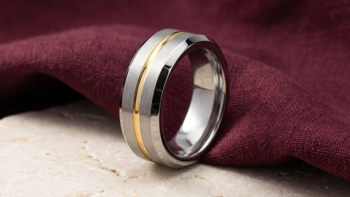 MAESTRO brushed silver tungsten wedding band with a thin gold groove on burgundy linen