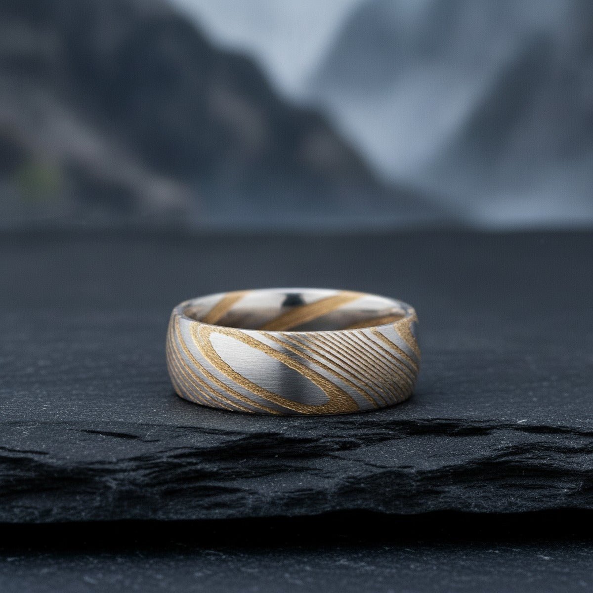 Aydins CERSEI | Damascus Steel Gold Banding Pattern lifestyle scene, slate stone mountain