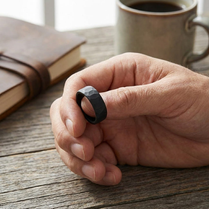 Aydins Jewelry Matte black tungsten hammered wedding band for men holding between two fingers