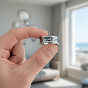 CHAZY — Held between fingers close-up — men's tungsten wedding ring.