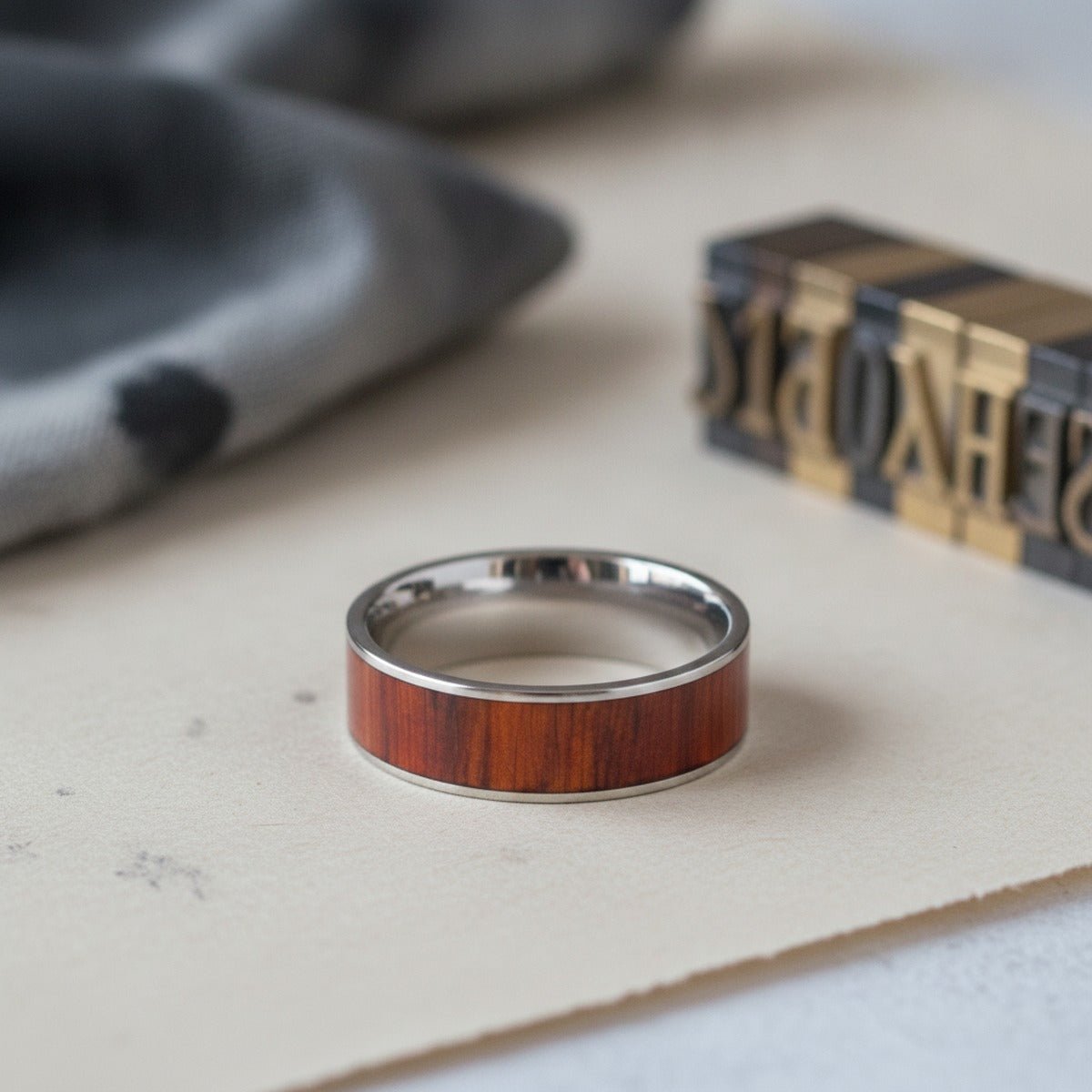 Aydins CLAYMORE | Silver Tungsten Ring, Exotic Padauk Wood Inlay, Flat lifestyle scene, letterpress print