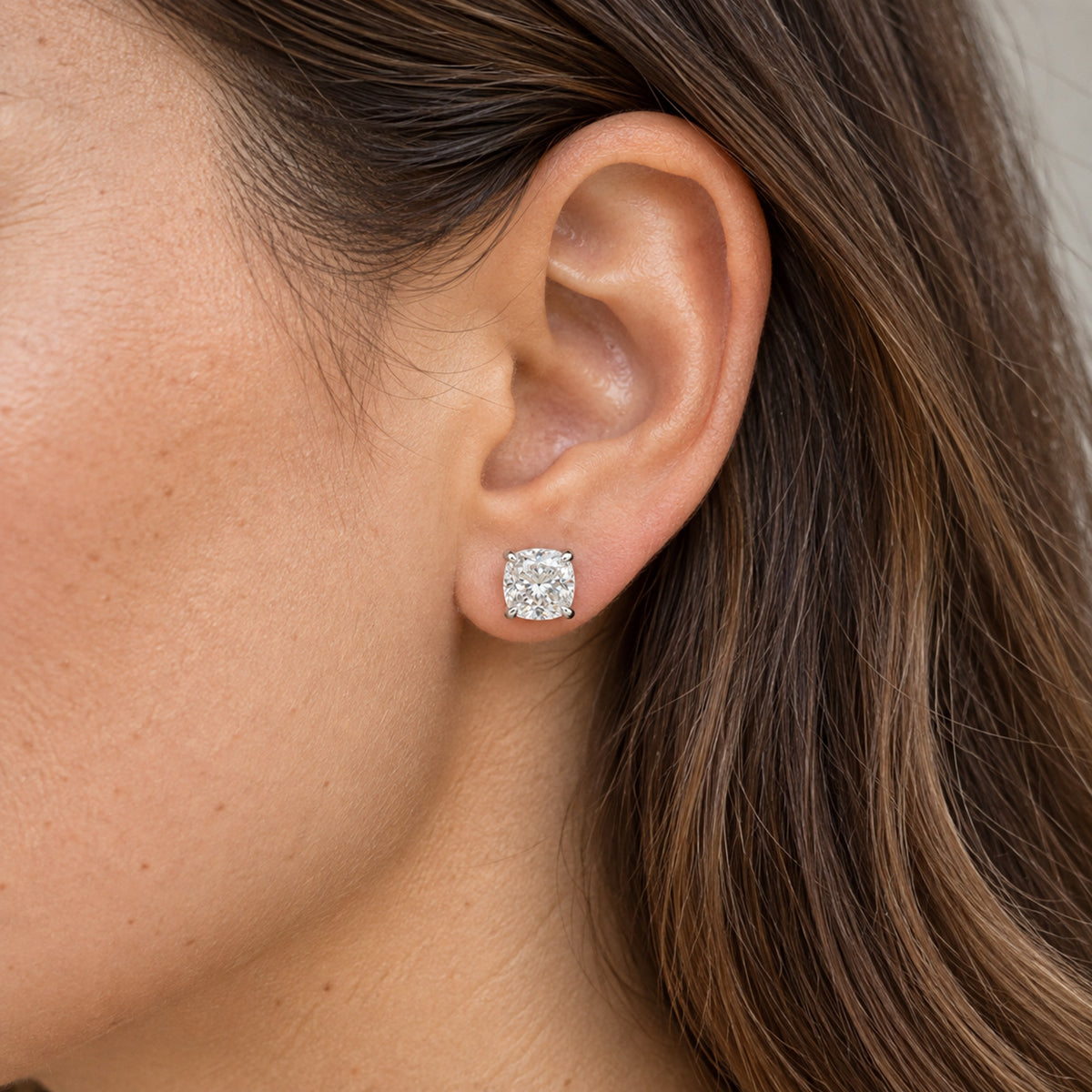 Cushion-cut lab-grown diamond stud earrings, worn on the ear, lifestyle photo