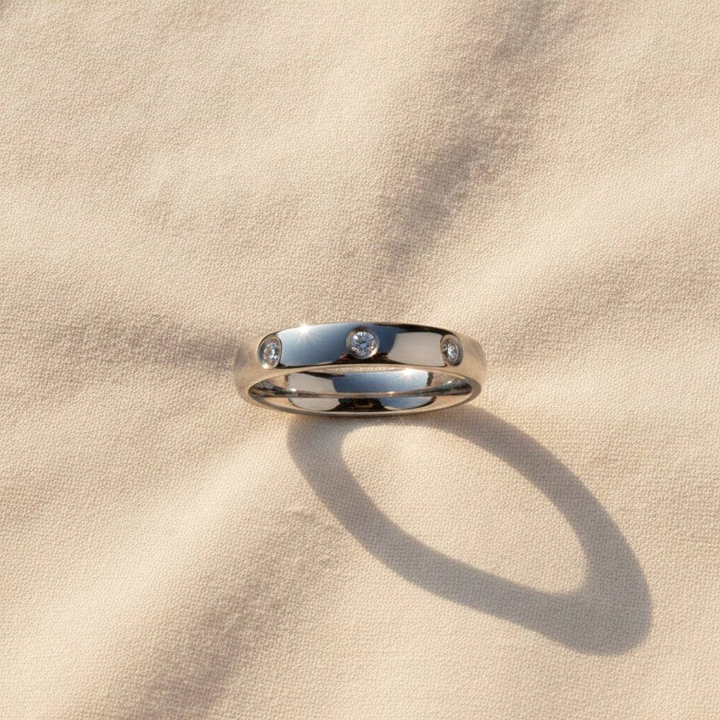 ISABELLA domed white tungsten wedding band with three small diamond accent stones set in a row on the center of the band and polished edges macro detail overhead flat lay