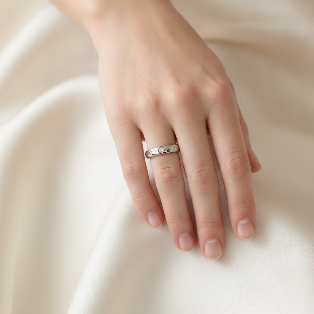 ISABELLA domed white tungsten wedding band with three small diamond accent stones set in a row on the center of the band and polished edges worn on a woman's hand, lifestyle photo