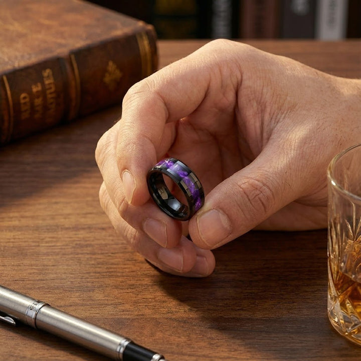 LUSTERS Black Tungsten Ring with Purple Tiger Cowrie Inlay holding between two fingers