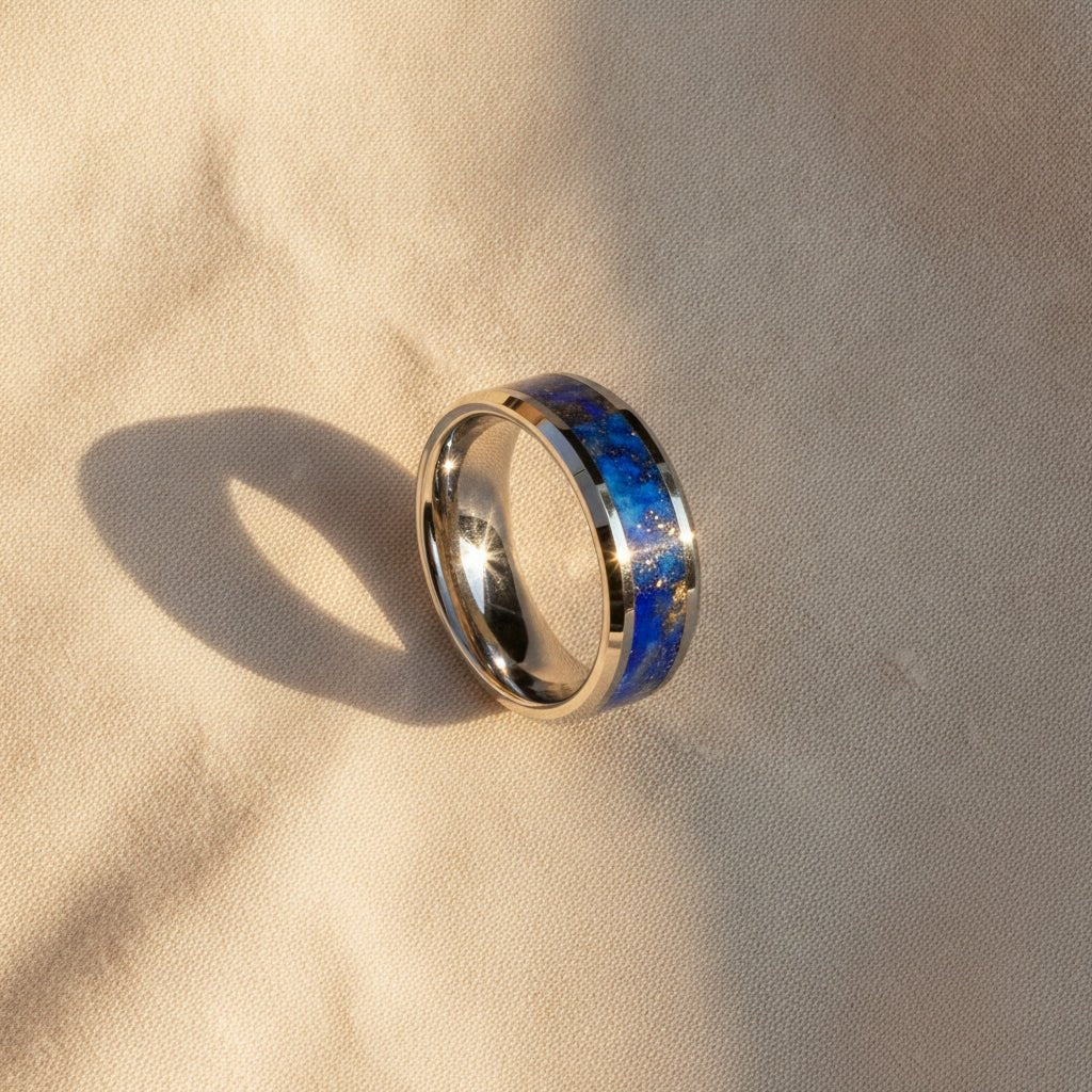 OSIAS polished silver tungsten wedding band with blue lapis stone inlay running around the band and polished beveled edges macro detail overhead flat lay