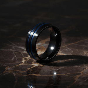 PETROS — Luxury 3/4 angle on dark marble — men's tungsten wedding ring.