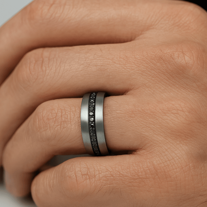 Close-up of a hand wearing a silver ring with black stones. 