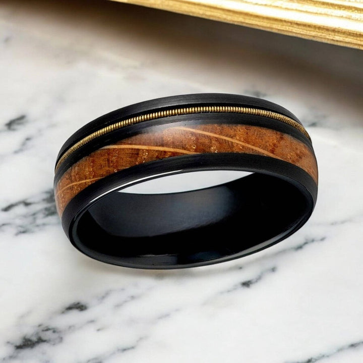 Close-up of the whiskey barrel and guitar string inlay on black tungsten wedding band.