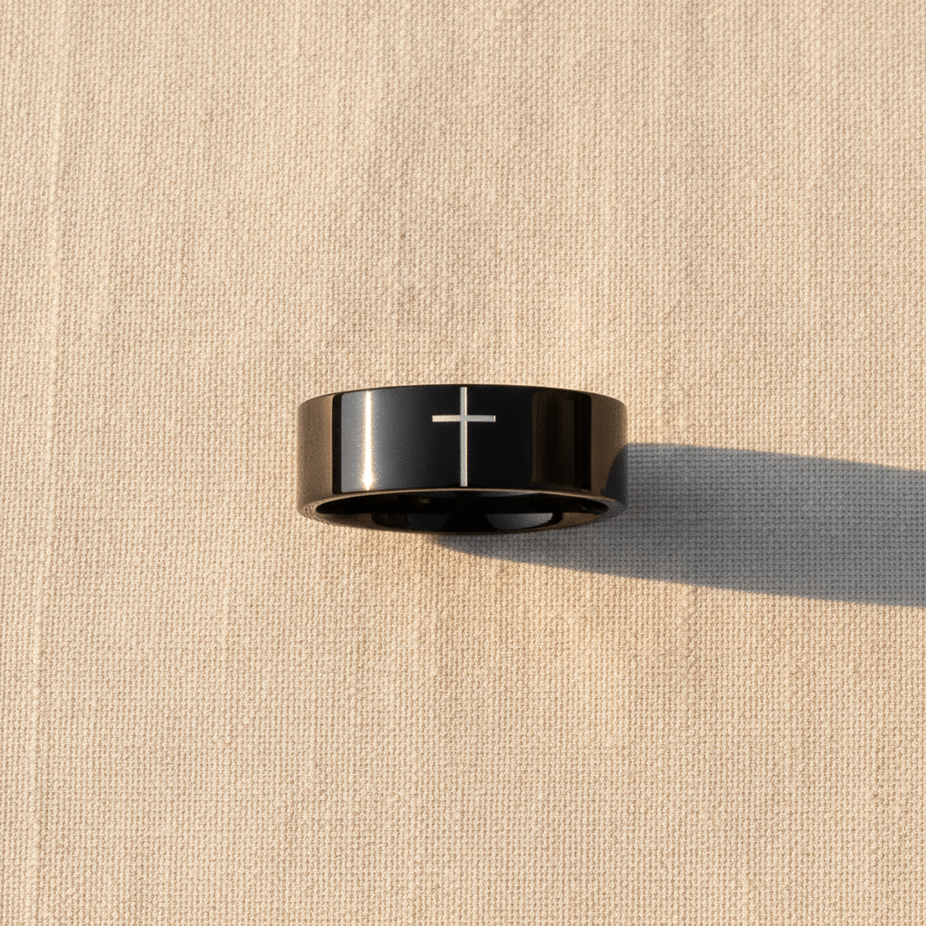 SANCTUS black tungsten wedding band with minimalist cross engraving macro detail overhead flat lay