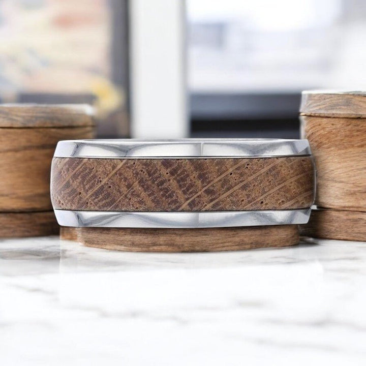 Close-up of STAVE ring showing whiskey barrel wood grain and polished titanium edges.