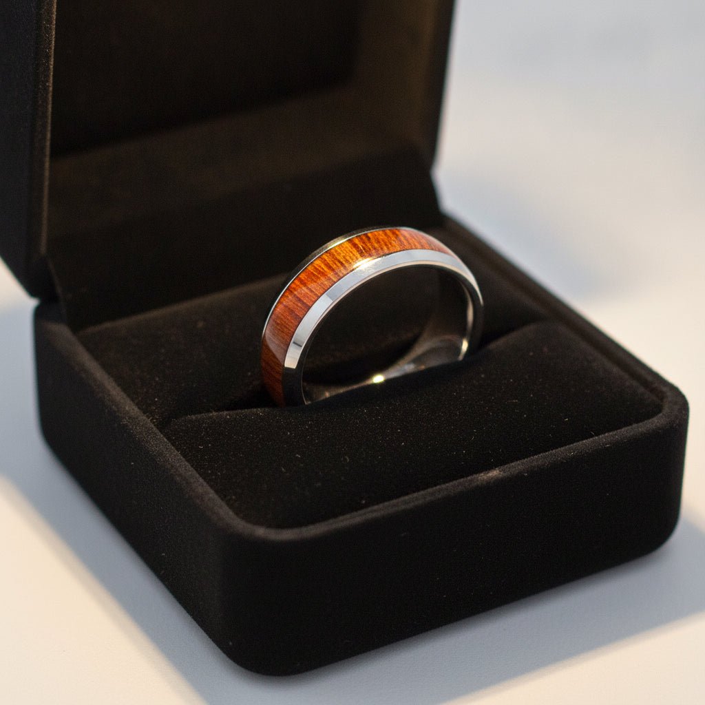 SWIETENIA silver tungsten wedding band with rich mahogany wood inlay running around the band and polished edges nested in a black velvet ring box, editorial jewelry shot