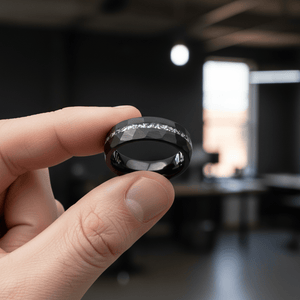 TITANIS — Held between fingers close-up — men's tungsten wedding ring.